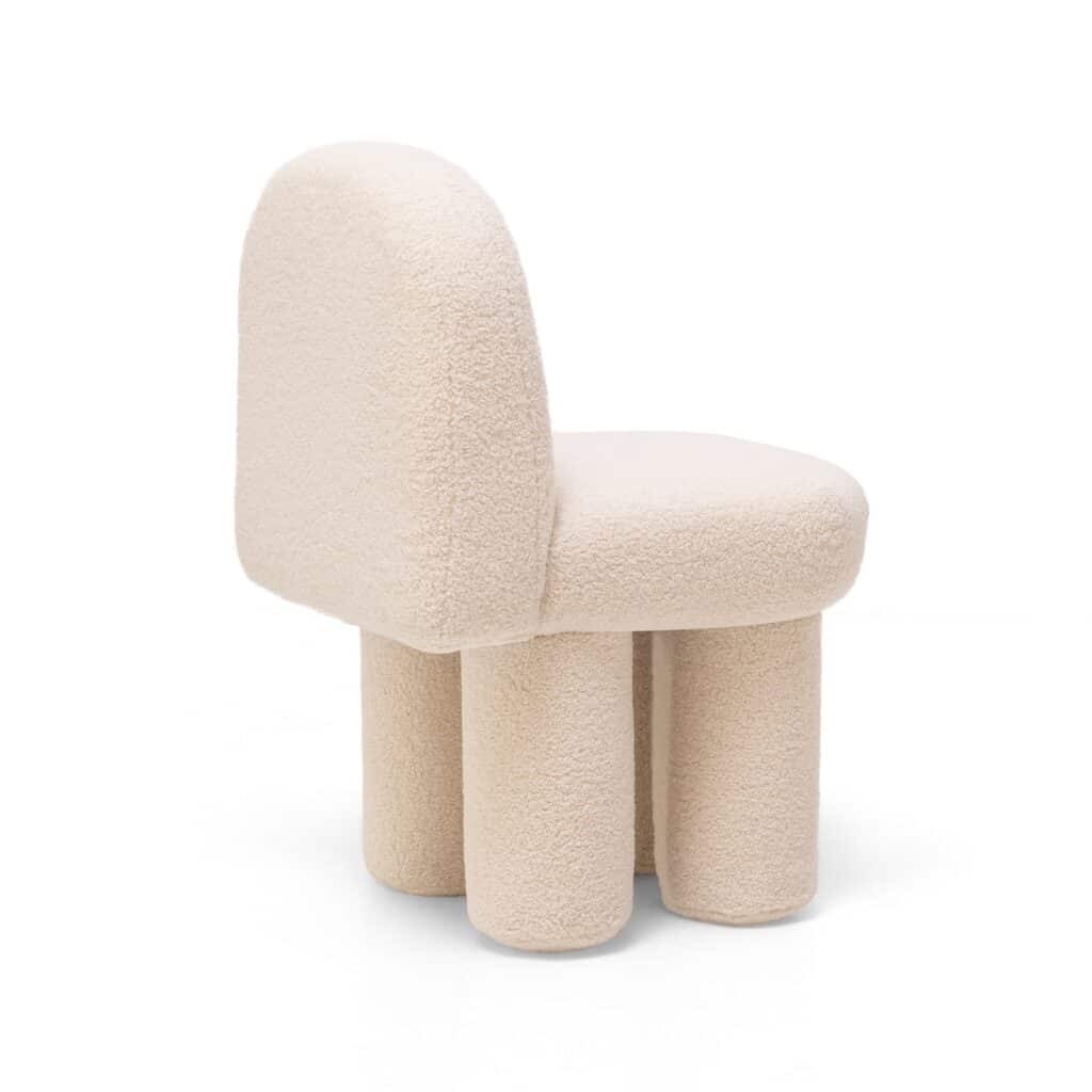 Fauteuil design bouclette beige à dossier arrondi. Le siège repose sur quatre pieds épais, style mobilier organique et doux.