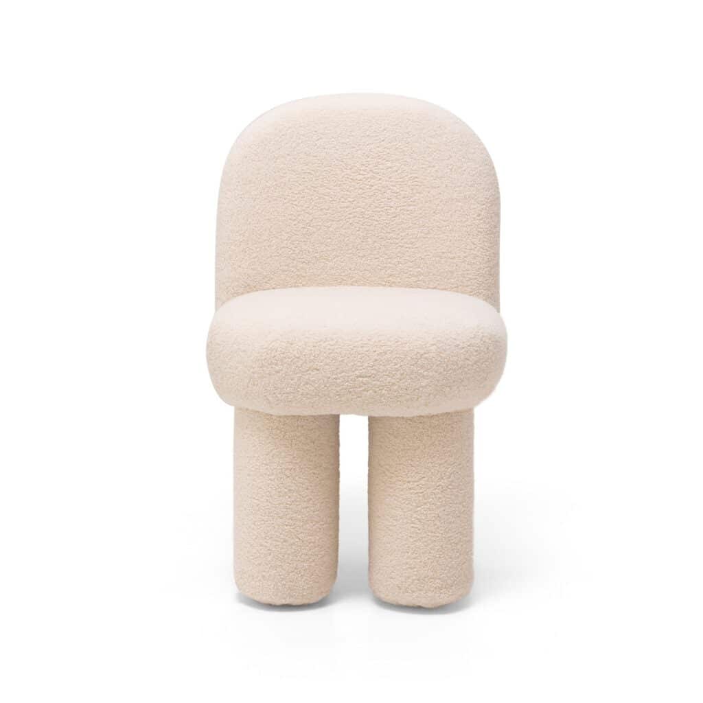 Fauteuil rembourré sculptural en bouclé beige. Dossier arrondi, assise cylindrique et deux pieds épais pour un design moderne Teddy.